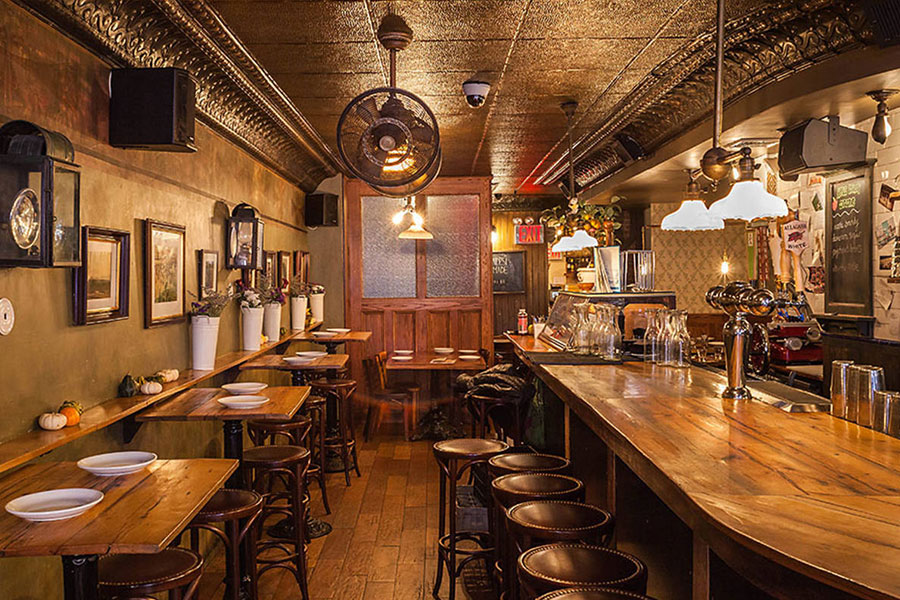 Interior of Rubirosa- Wooden bar, bar stools, and high top tables