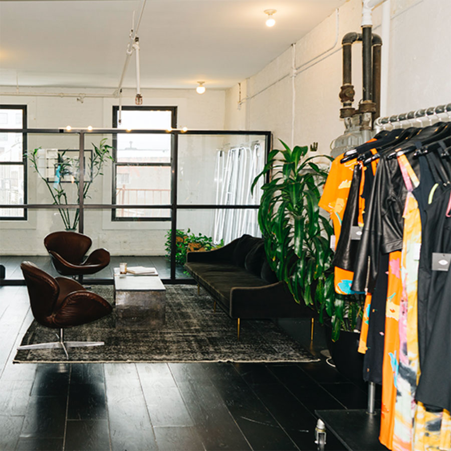 Clothing hanging on a clothing rack near a large rug and seating area