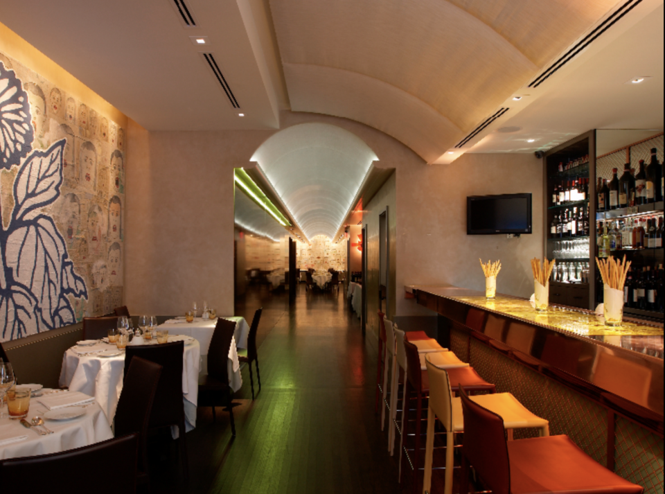 Inside of the restaurant Caravaggio, with circular tables by the wall and a bar counter a long corridor leader to another dining hall